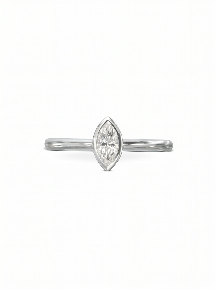 Marquise cut diamond engagement ring in a silver-toned bezel setting on a plain polished band.