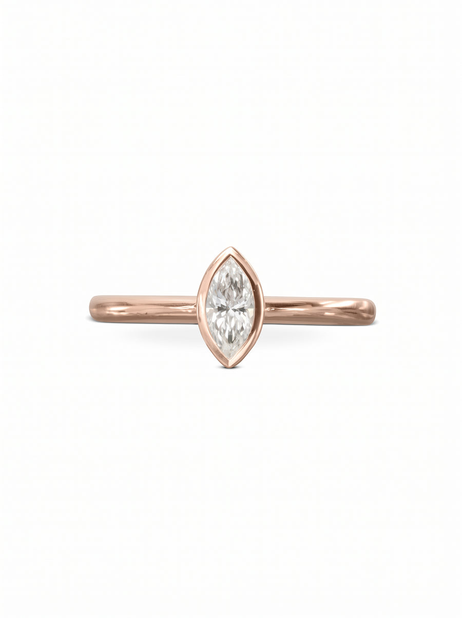 Marquise cut diamond engagement ring in a rose gold bezel setting on a plain band.