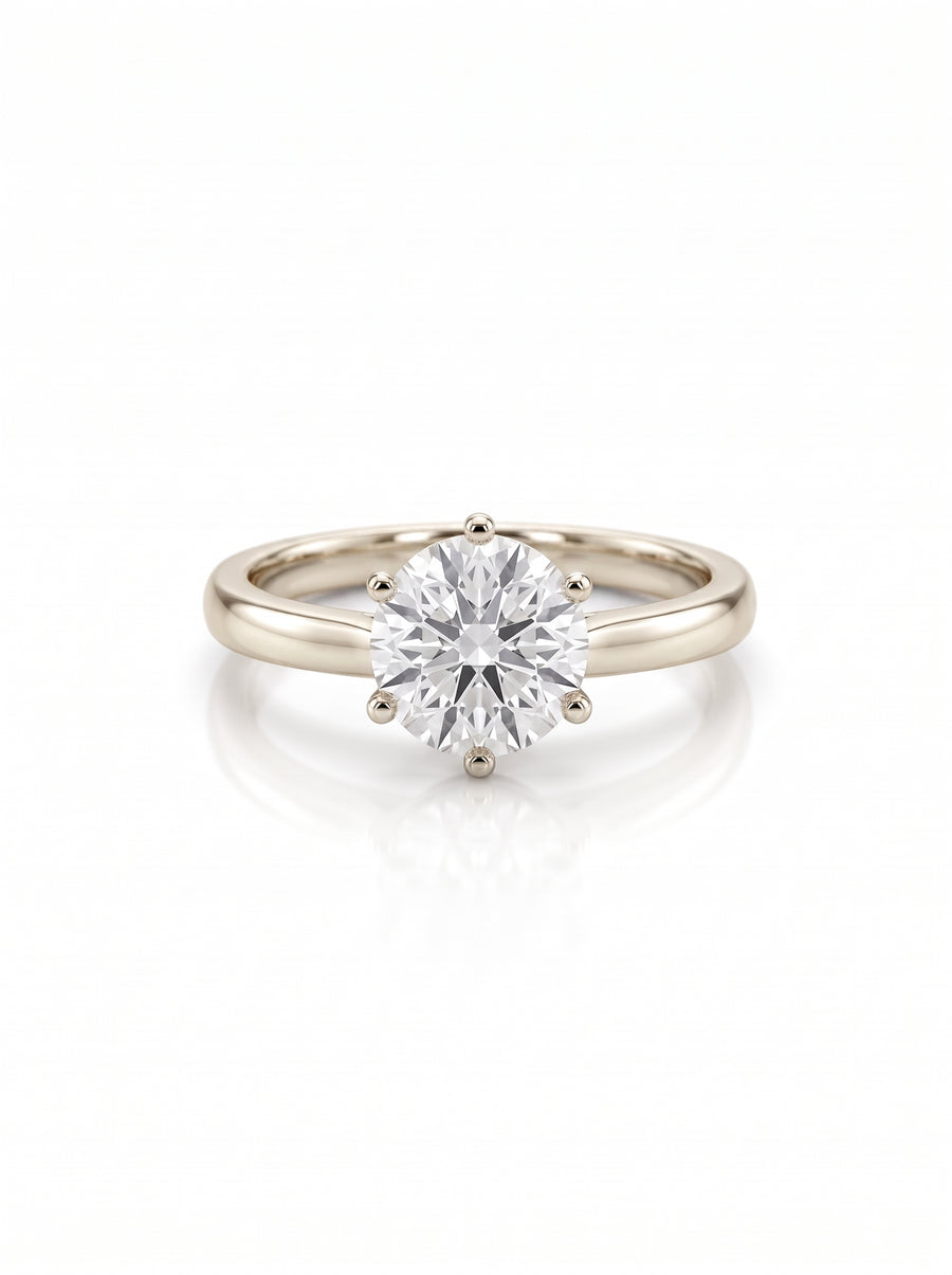 Round brilliant diamond solitaire engagement ring in a six-claw gold setting on a white background.