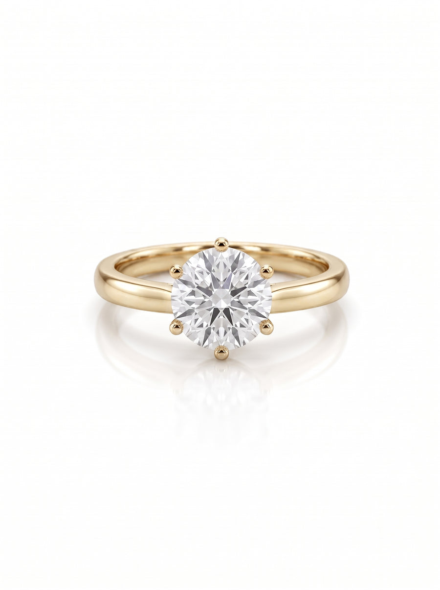 Round brilliant diamond solitaire engagement ring in a six-claw yellow gold setting on a white background.