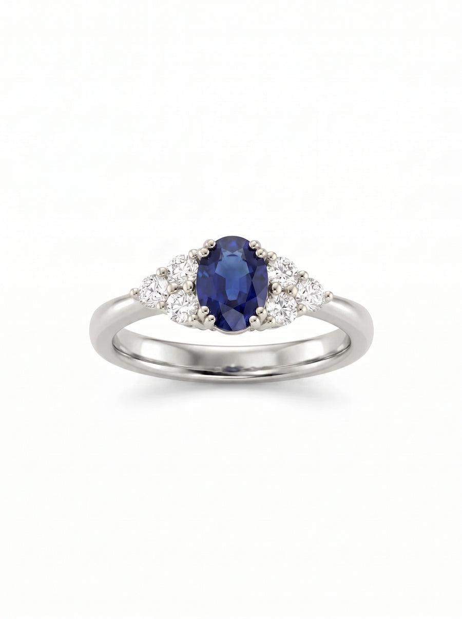 Oval blue sapphire and round diamond trefoil engagement ring set in polished white gold.