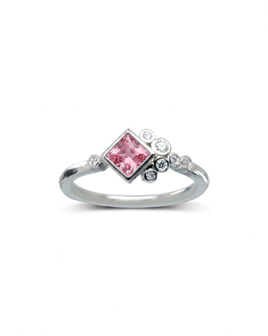 Silver engagement ring featuring a princess-cut pink gemstone accented by a cluster of small round diamonds.
