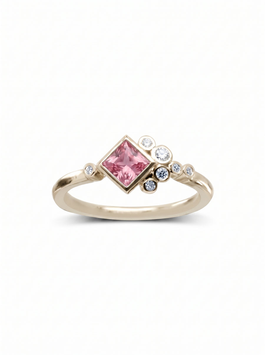 Gold engagement ring featuring a square pink gemstone accented by a cluster of small round diamonds.