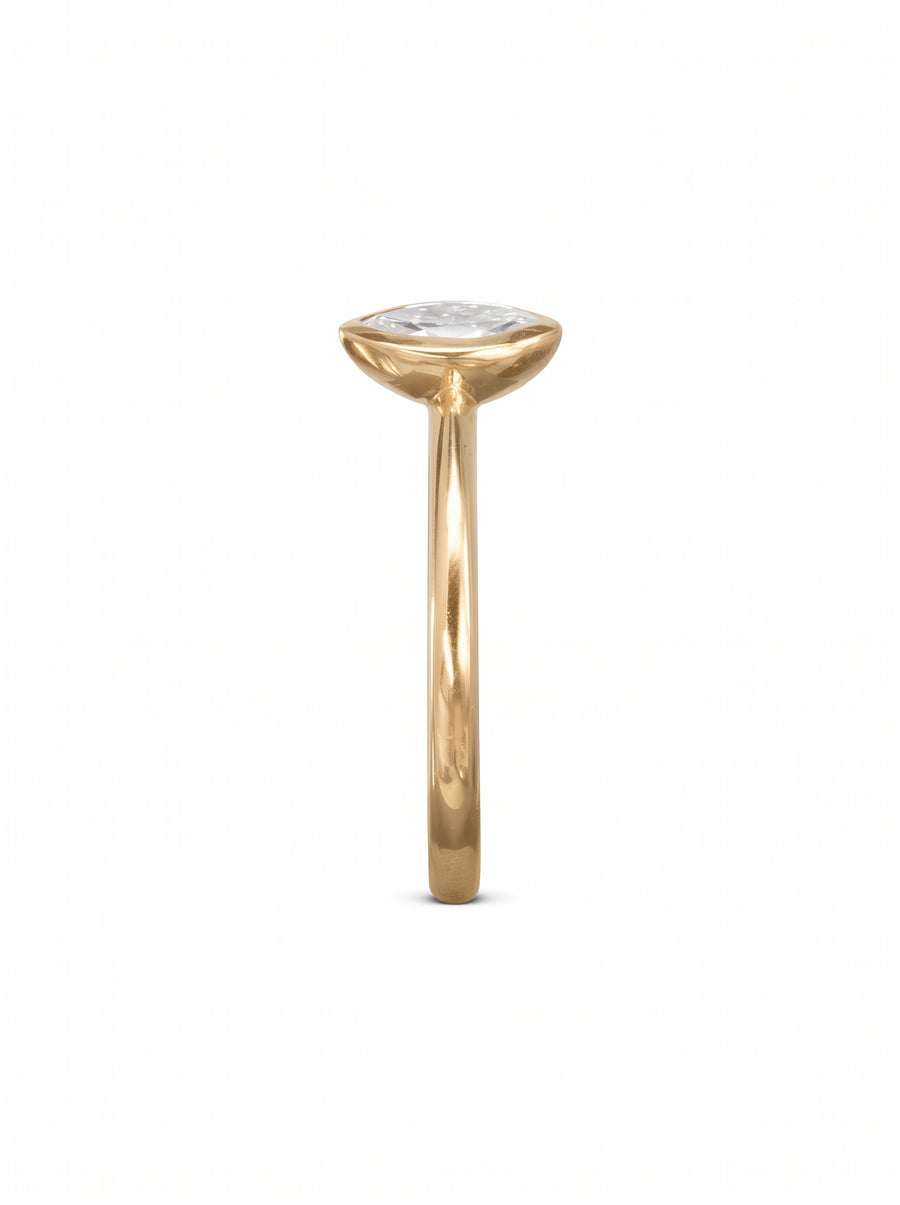 Gold engagement ring with a marquise cut diamond in a bezel setting, viewed from the side.