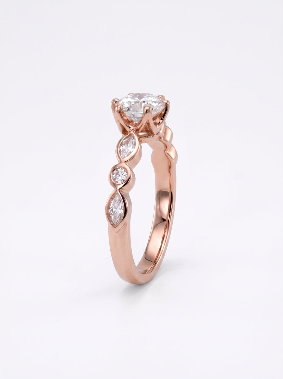 Rose gold engagement ring with a round cut center stone and marquise and round accent diamonds.