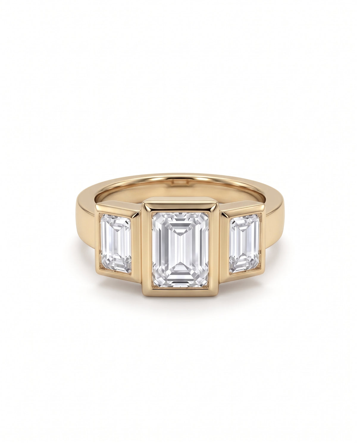 Gold trilogy ring featuring three bezel-set emerald cut diamonds in an Art Deco style.