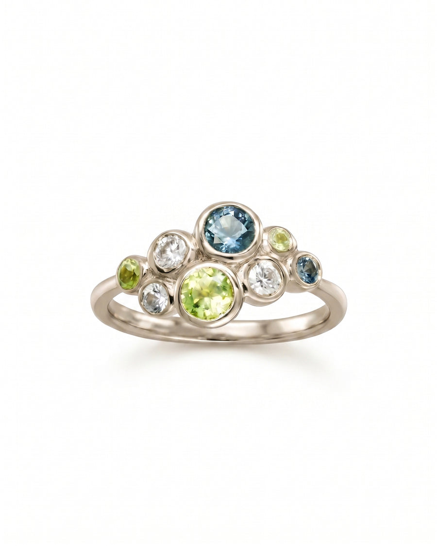 Cluster ring in silver featuring bezel-set green and teal sapphires and clear stones in a bubble design.