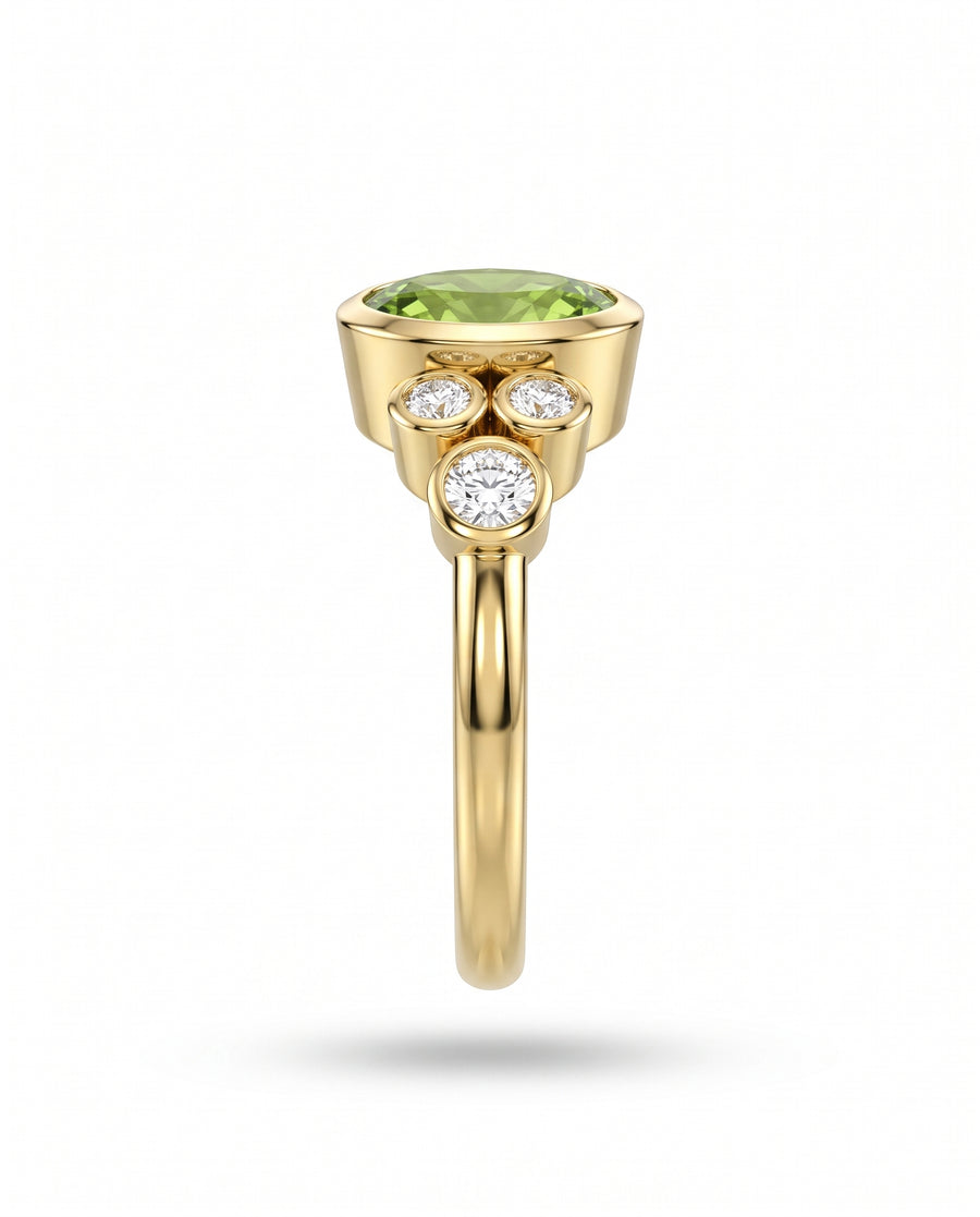 Gold dress ring featuring a large oval green gemstone and three bezel-set round diamonds.