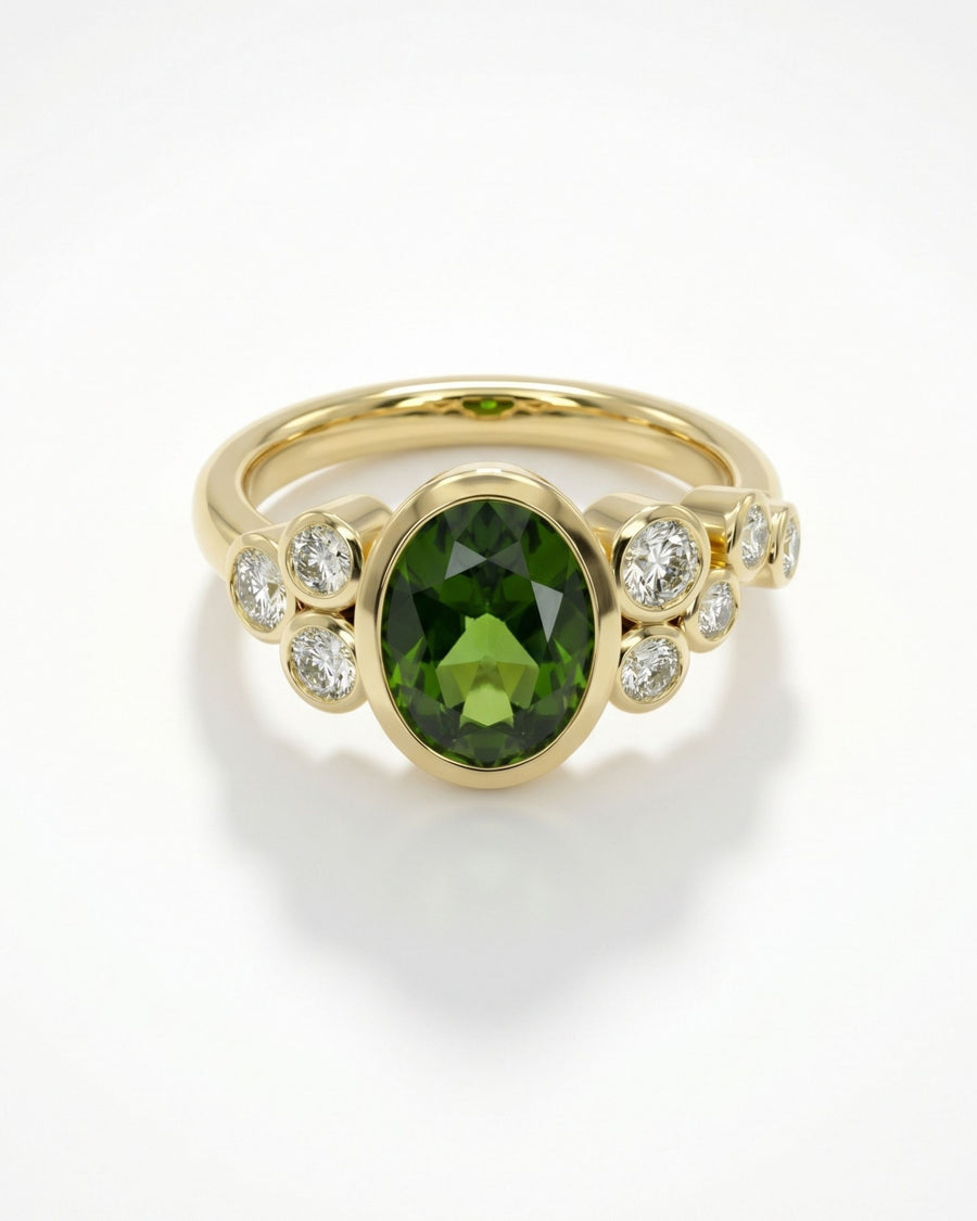 Oval green gemstone ring in yellow gold with bezel-set diamond accents along the band.