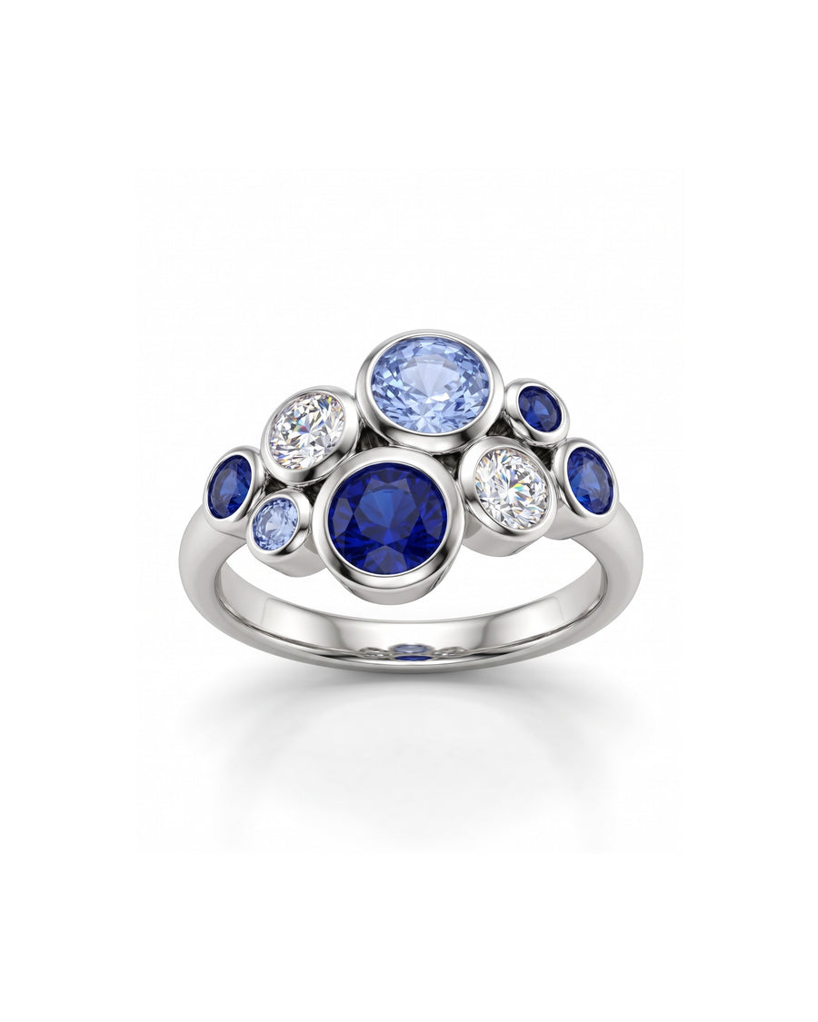 Platinum cluster ring featuring bezel-set round blue sapphires and clear diamonds in a bubble design.