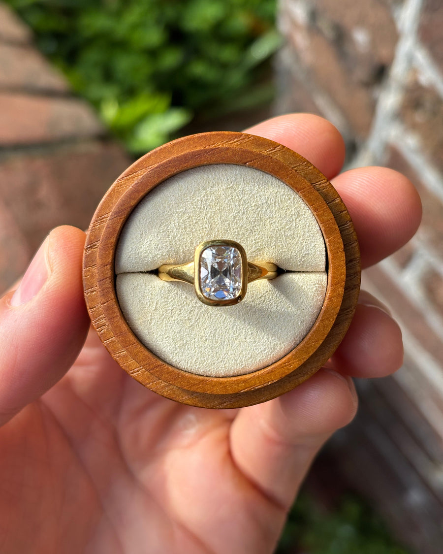 2.57ct cushion cut diamond engagement ring in a 9ct yellow gold bezel setting held in a wooden box.