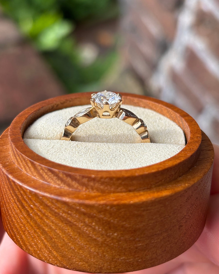Round cut lab-grown diamond engagement ring in a gold crown setting inside a wooden box.
