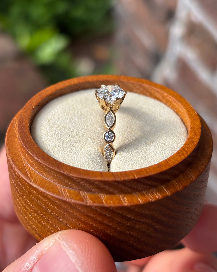 Round cut diamond engagement ring with marquise and round side stones in a yellow gold crown setting.