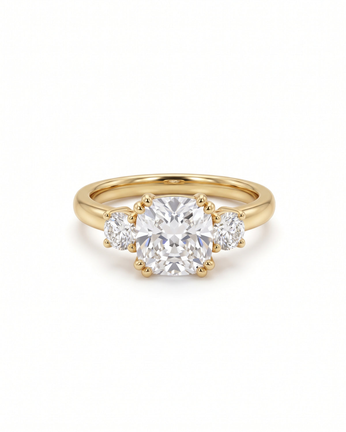 Trilogy engagement ring with a cushion cut center diamond and two round side stones set in yellow gold.