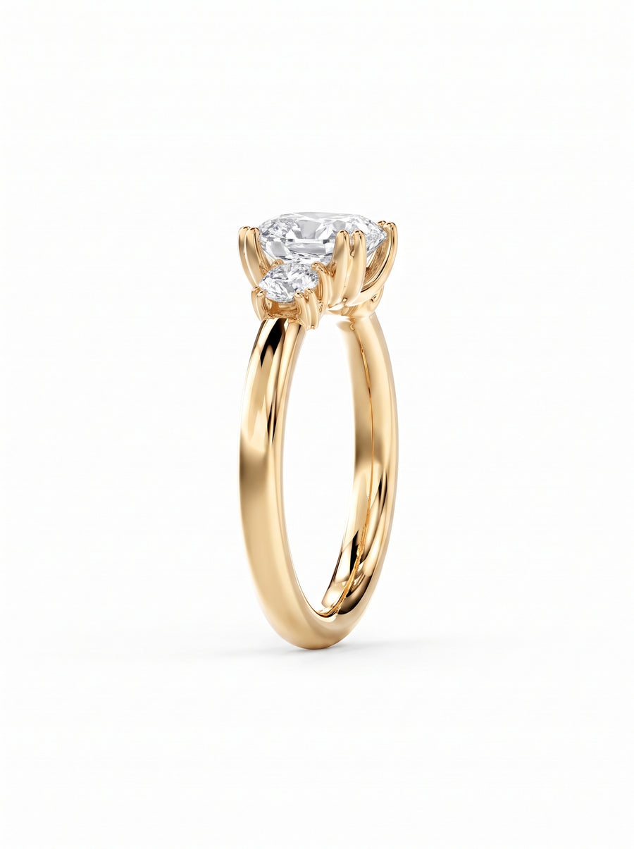 Yellow gold trilogy engagement ring featuring a cushion cut center diamond and two side round diamonds.