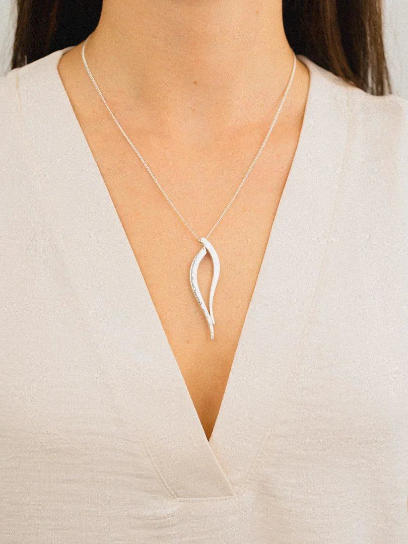 Woman wearing a handmade silver pendant necklace with an organic, leaf-inspired design