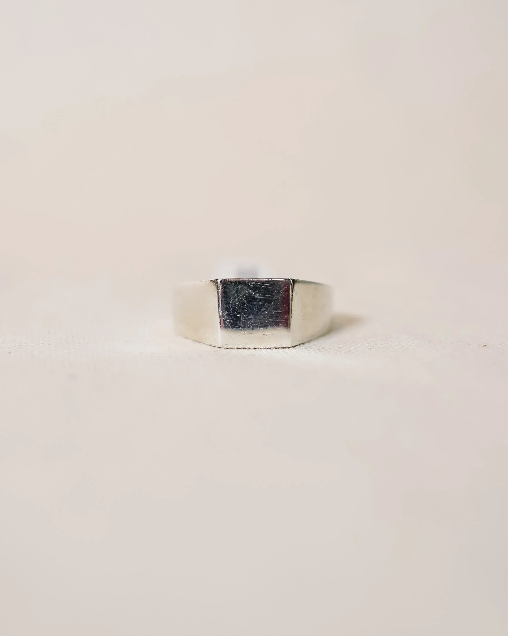Handmade silver signet ring with a polished, minimalist design on a light background