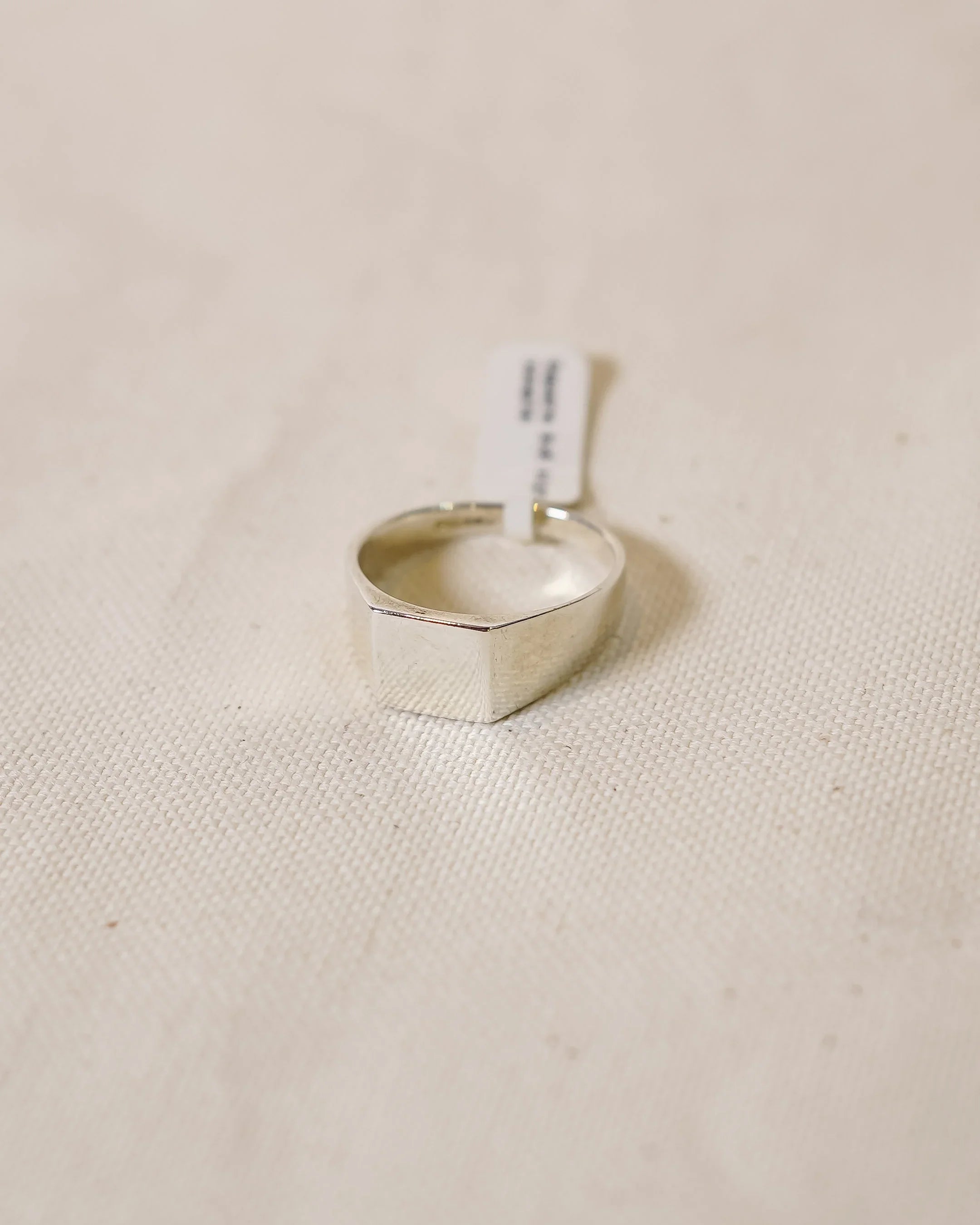 Handcrafted silver signet ring with a minimalist design on a soft fabric background