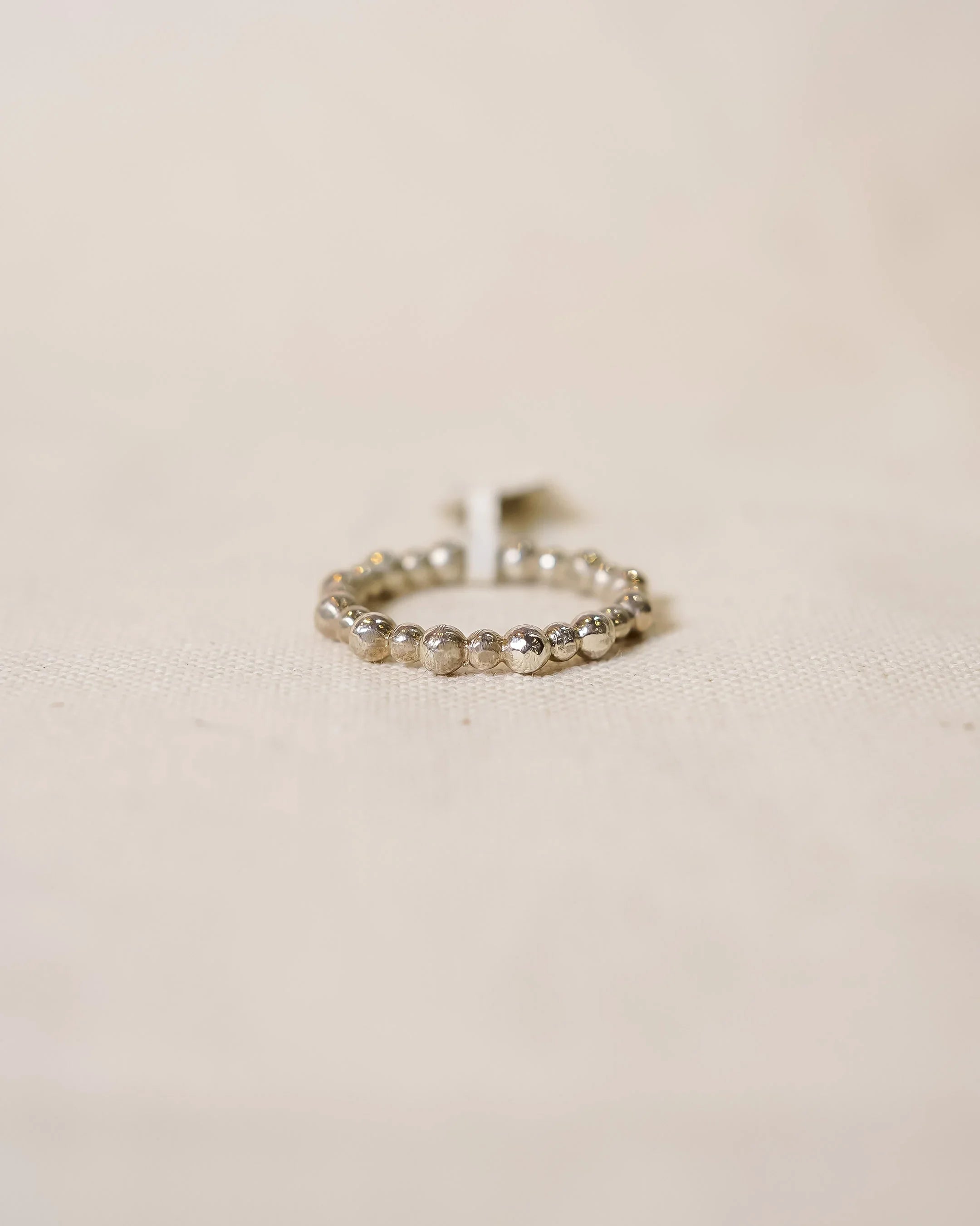 Handcrafted silver beaded ring with organic texture on a neutral fabric background