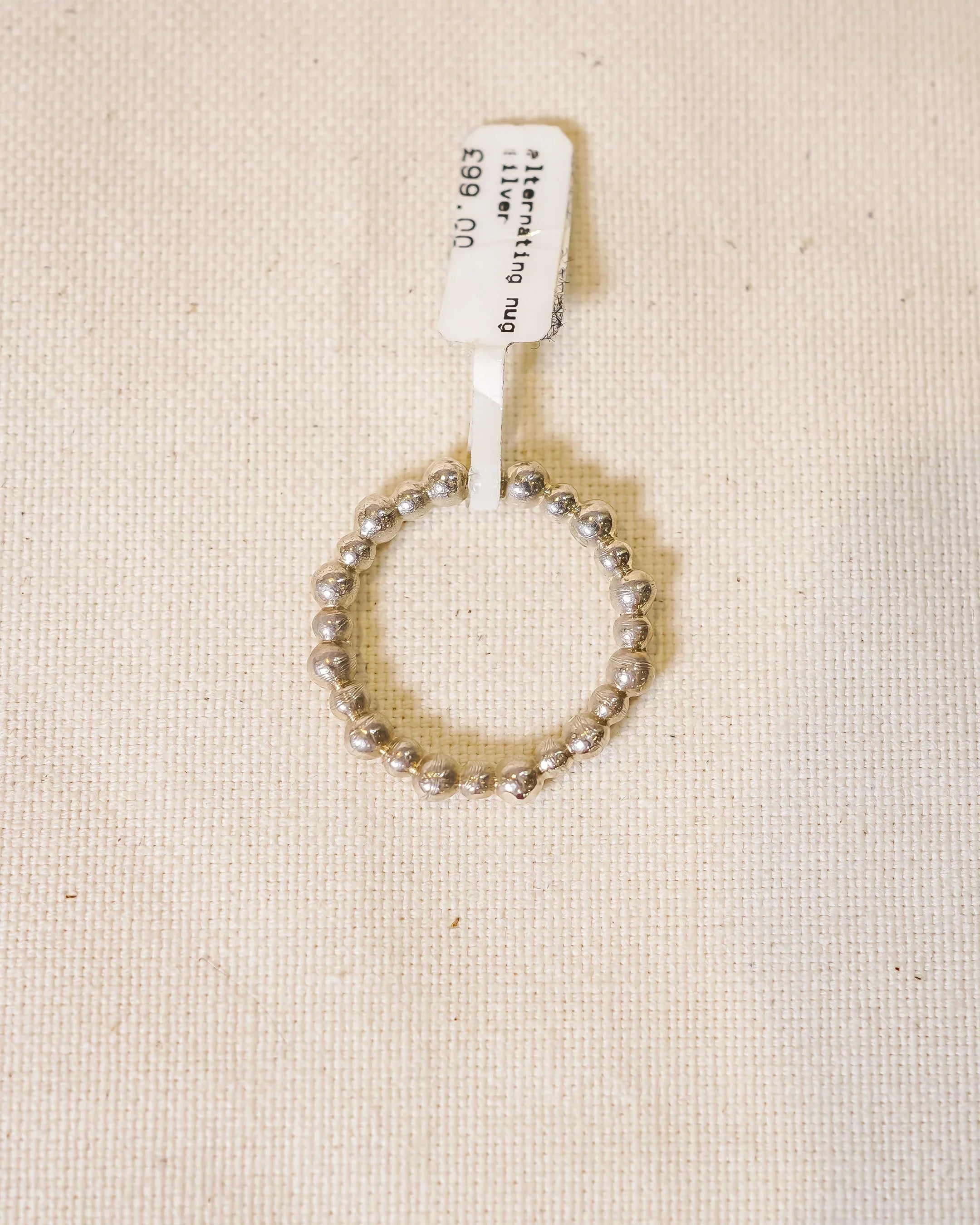 Handmade silver nugget ring with textured organic beads on neutral fabric background