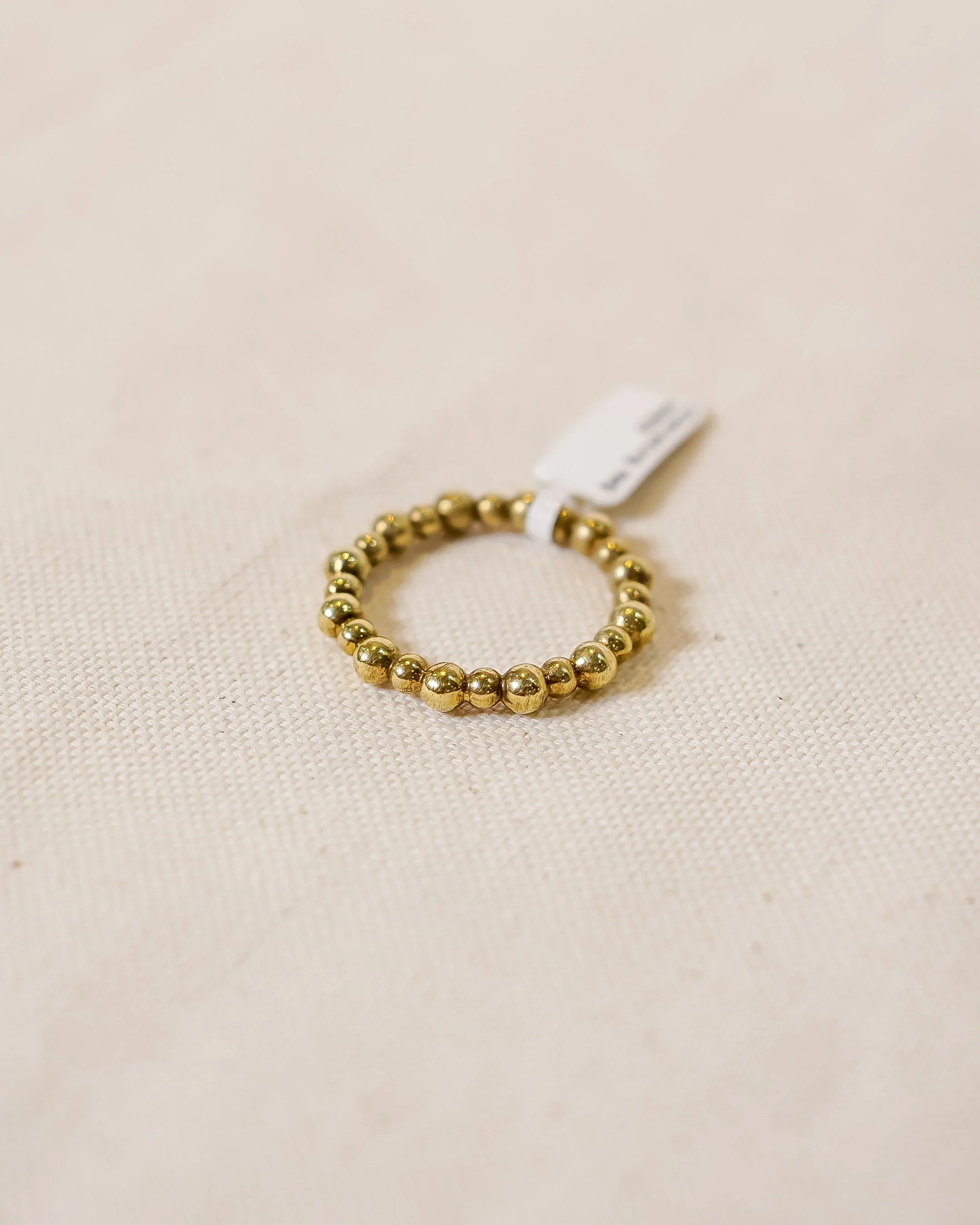 Handmade gold beaded ring with organic texture on cream fabric background