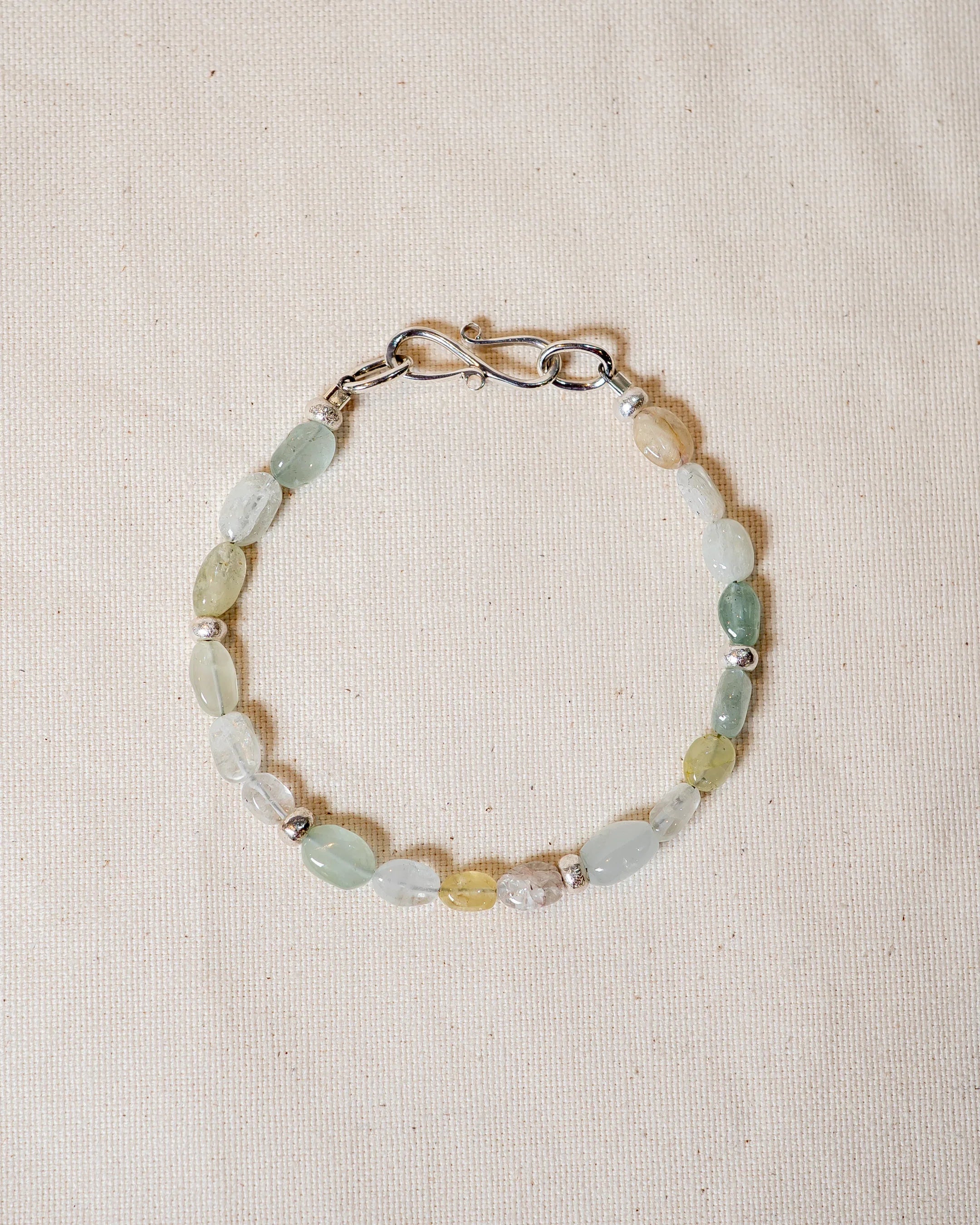 Handmade gemstone beaded bracelet with silver clasp on a neutral fabric background