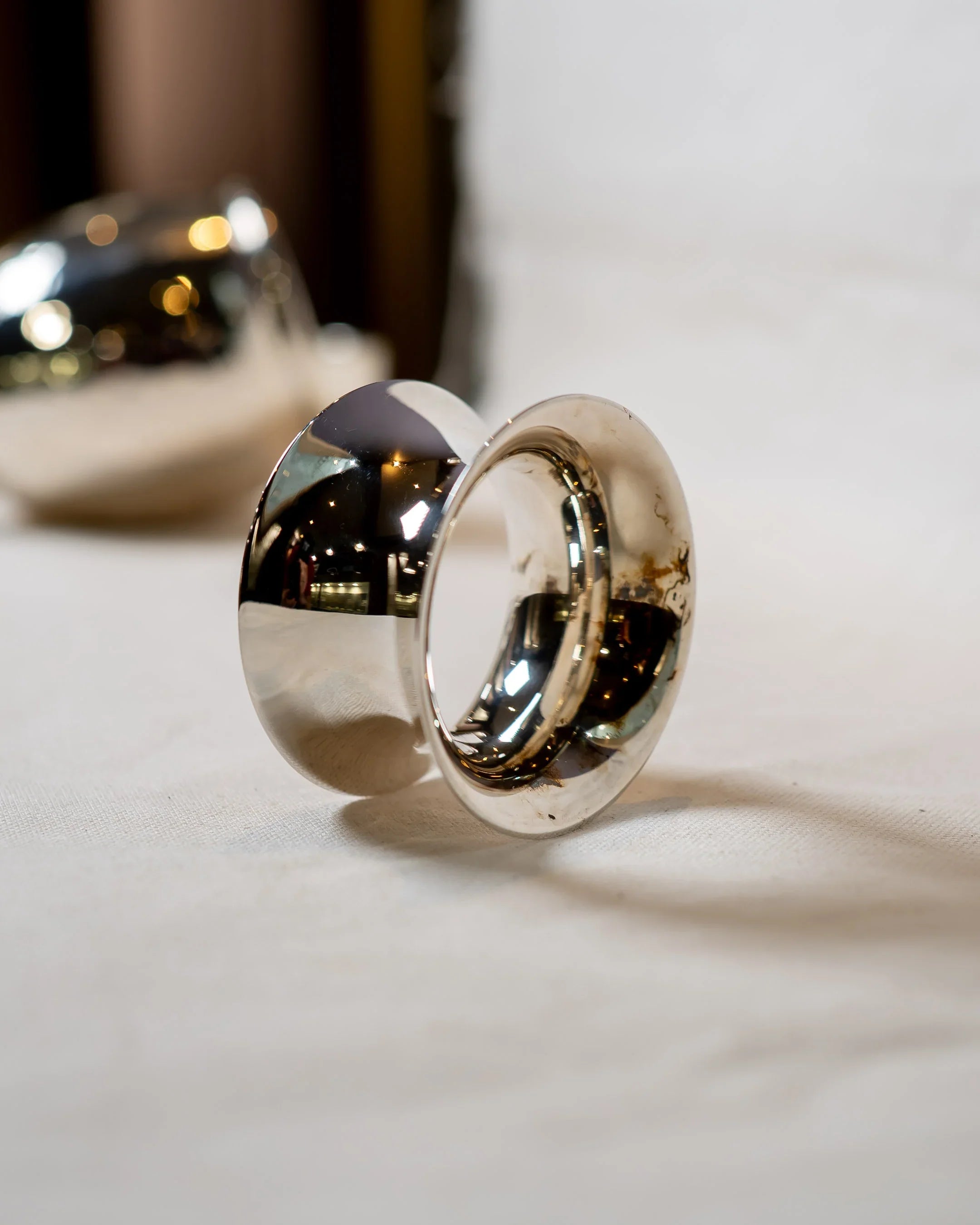 Polished silver statement ring with organic shape on white fabric background, luxury handmade jewellery