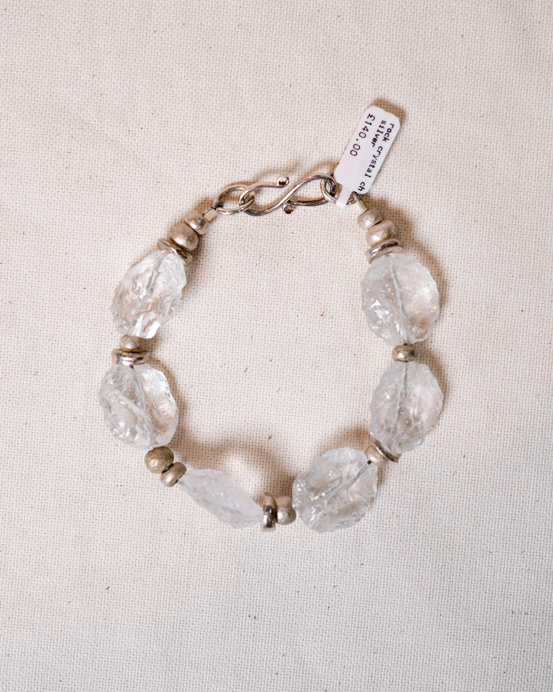 Handmade rock crystal and silver beaded bracelet on a neutral fabric background