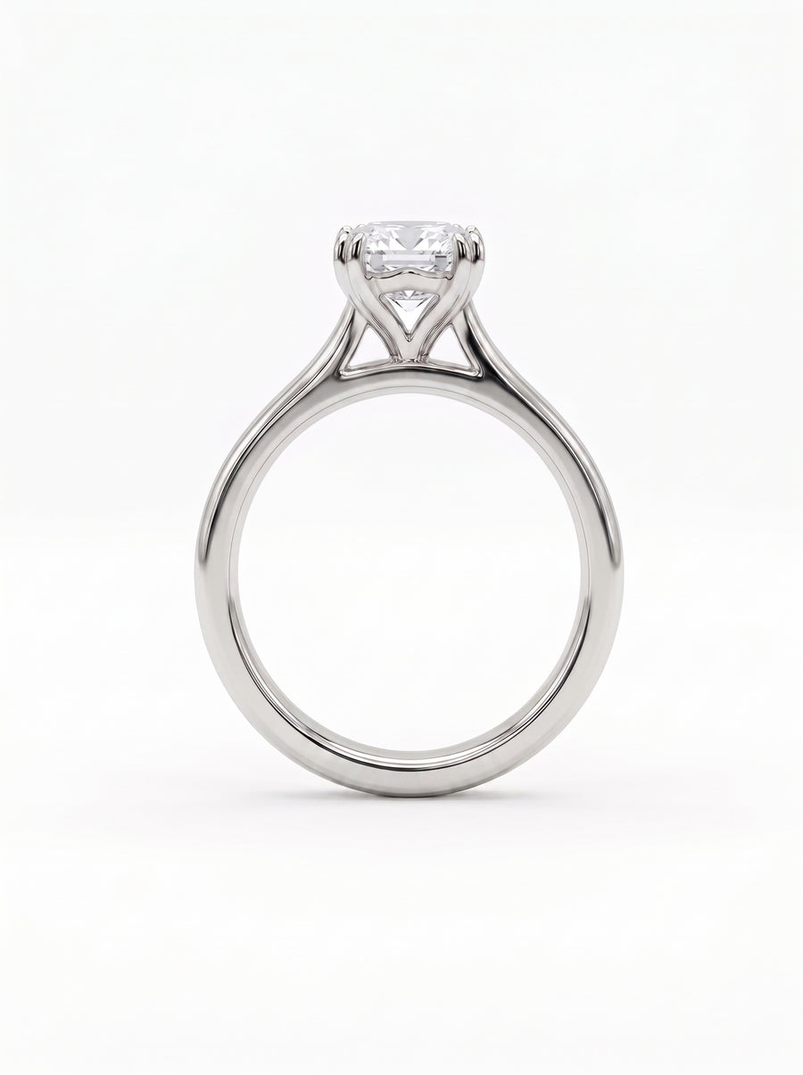 Emerald-cut solitaire engagement ring in polished silver metal with a cathedral setting on a white background.