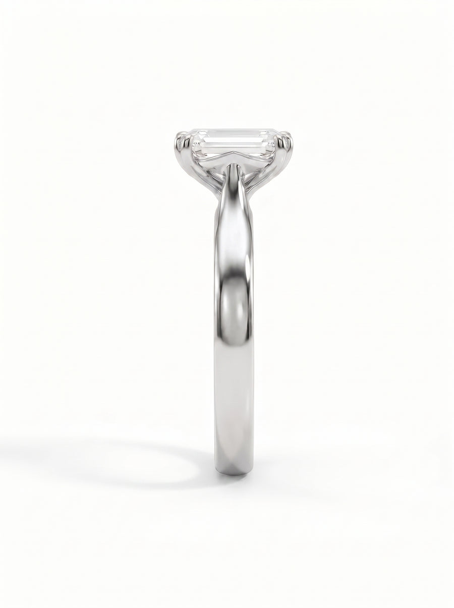 Emerald-cut solitaire engagement ring in polished platinum with a cathedral setting on a white background.