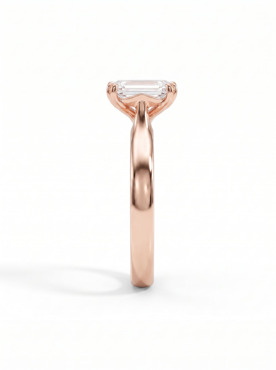 Emerald-cut diamond solitaire engagement ring set in a polished rose gold cathedral band.