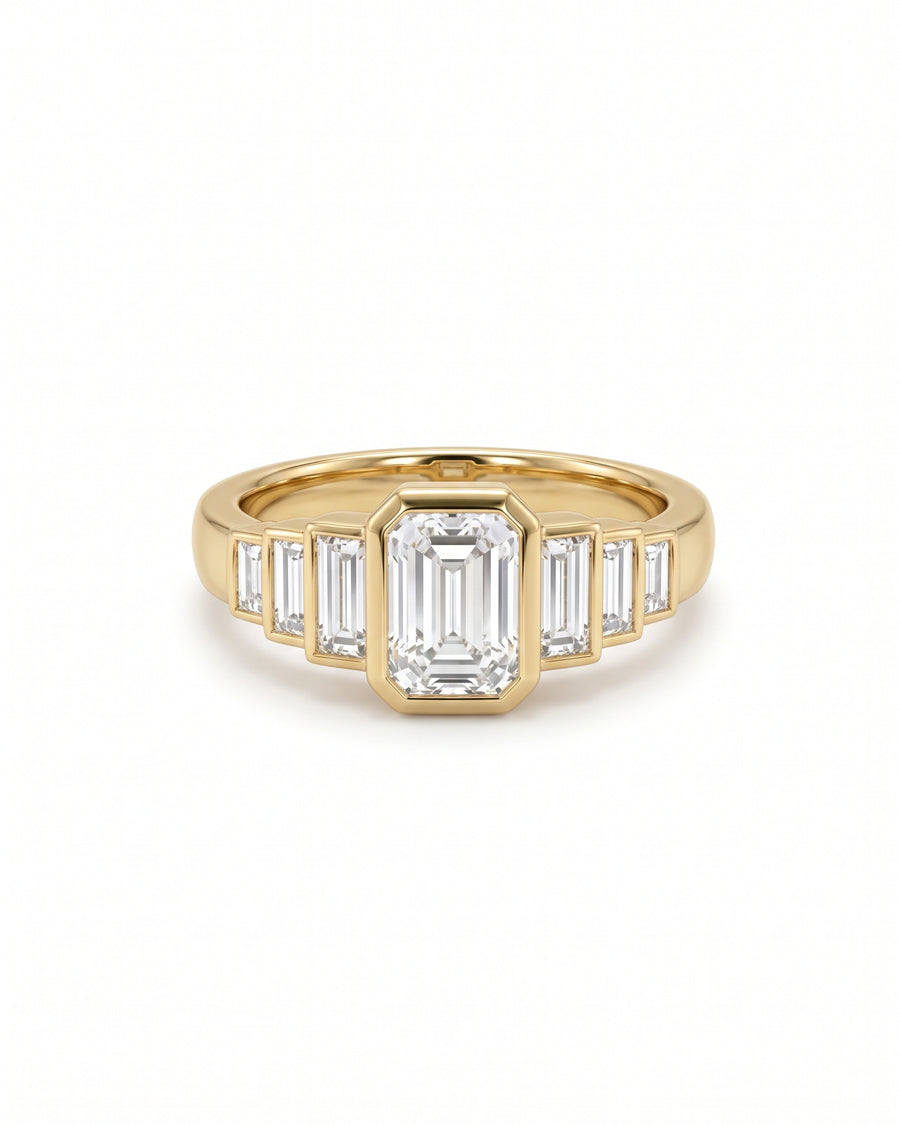 Gold engagement ring featuring a central emerald-cut diamond flanked by three baguette-cut diamonds on each side.
