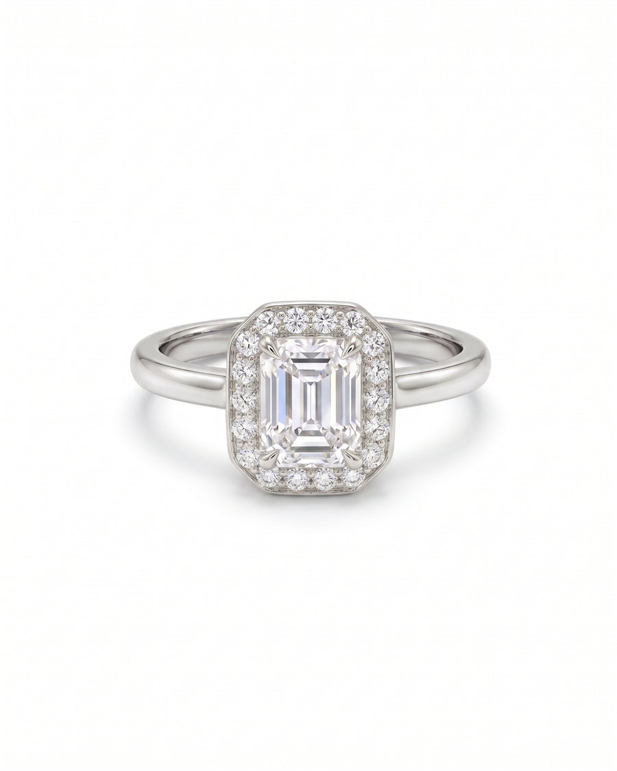 Emerald-cut diamond engagement ring with a diamond halo set in polished white gold.