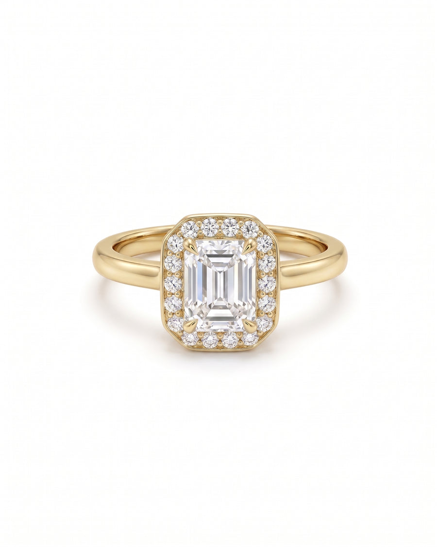 Emerald-cut diamond engagement ring with a diamond halo set in a yellow gold band.