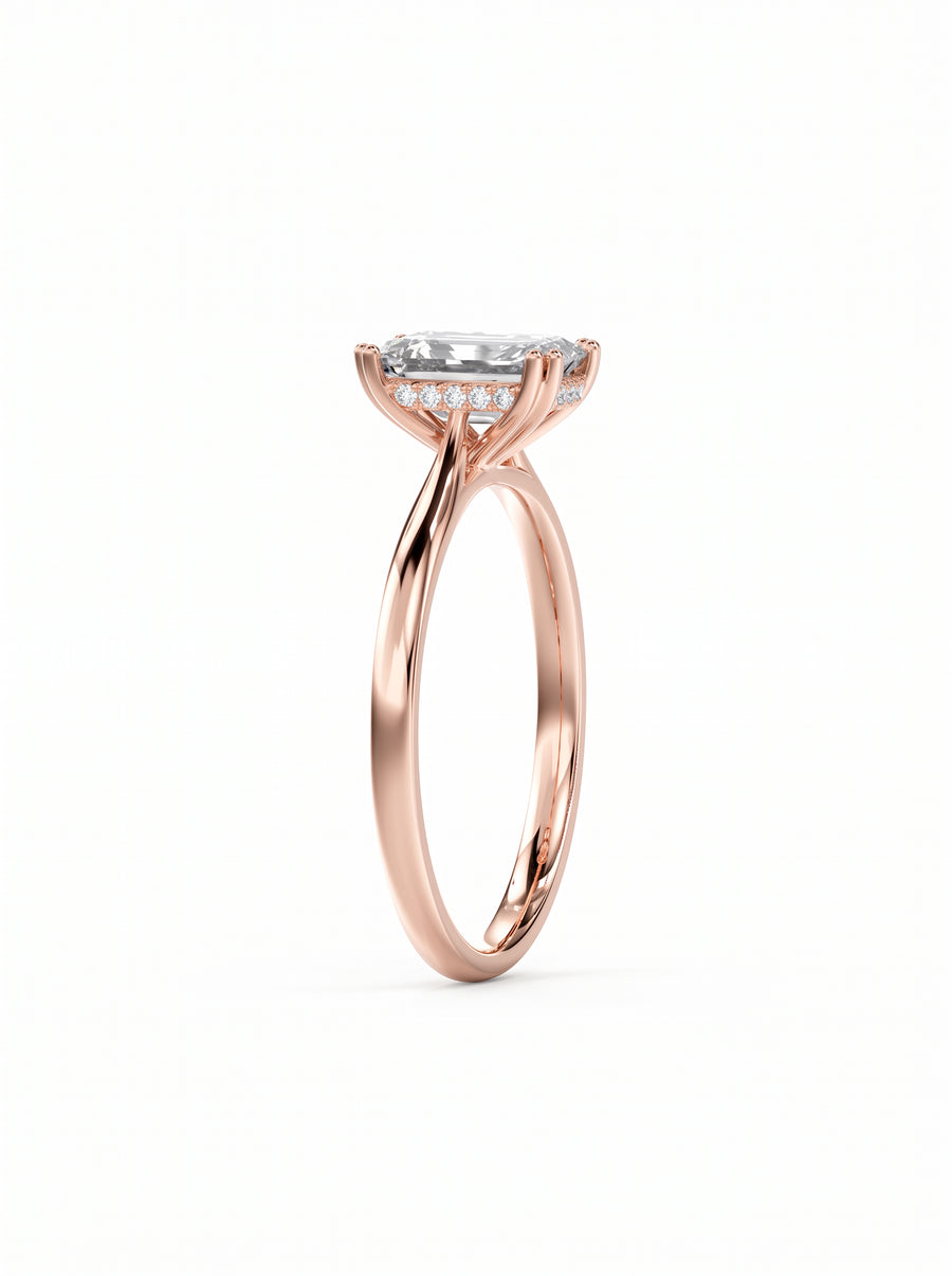 Emerald cut diamond engagement ring in rose gold with a hidden halo of small accent stones.