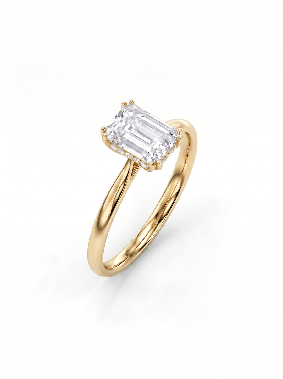 Emerald cut diamond engagement ring with a hidden halo on a polished yellow gold band.