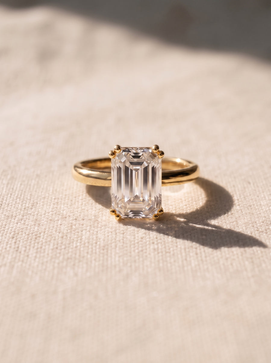 Emerald cut diamond engagement ring with a hidden halo on a yellow gold band.