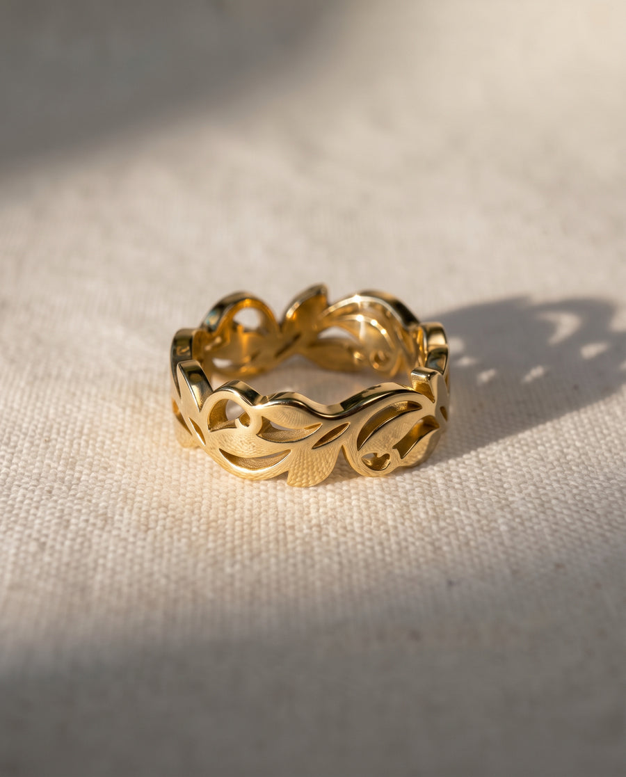 9ct yellow gold ring featuring a cutout floral leaf design on a textured cream background.