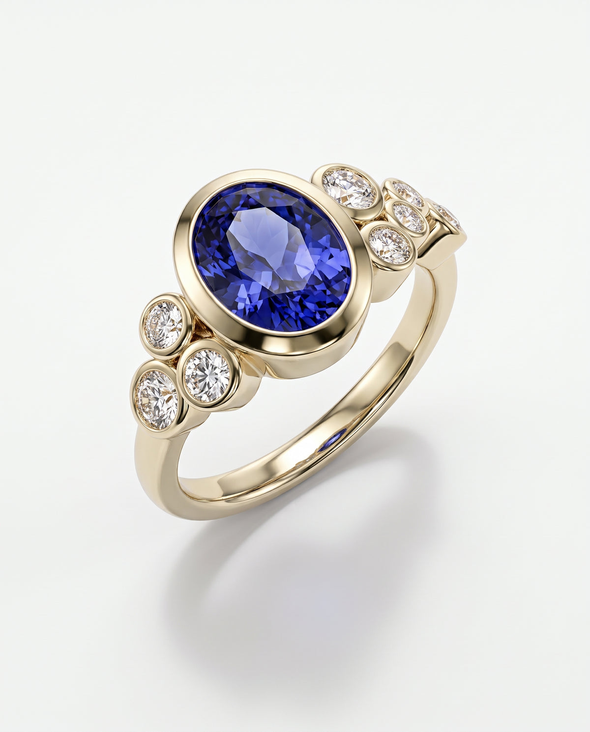 Oval tanzanite dress ring in yellow gold with bezel-set round diamond accents on a white background.