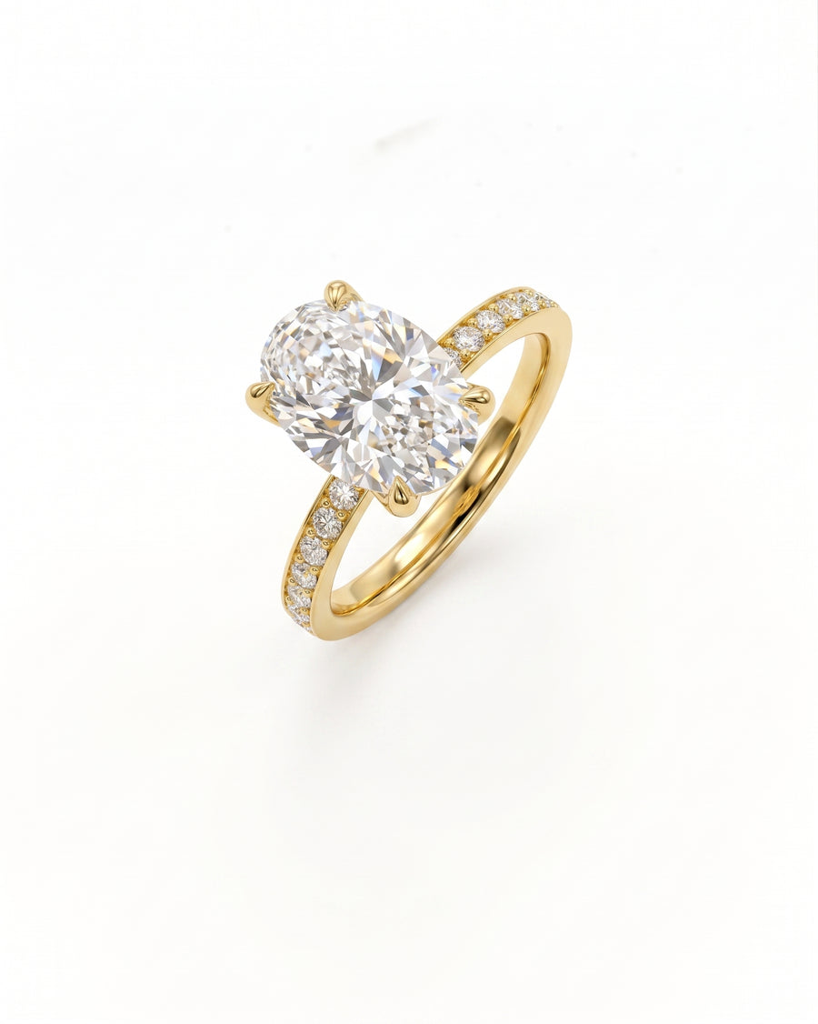 A yellow gold solitaire engagement ring featuring a large oval-cut diamond center stone and a pavé-set diamond band, shown on a clean white background.