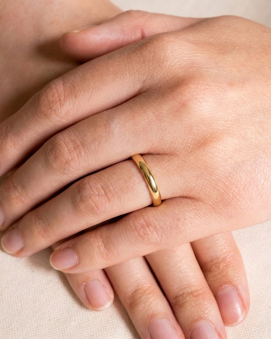 Simple yellow gold wedding band with a smooth, rounded profile worn on a woman's finger.
