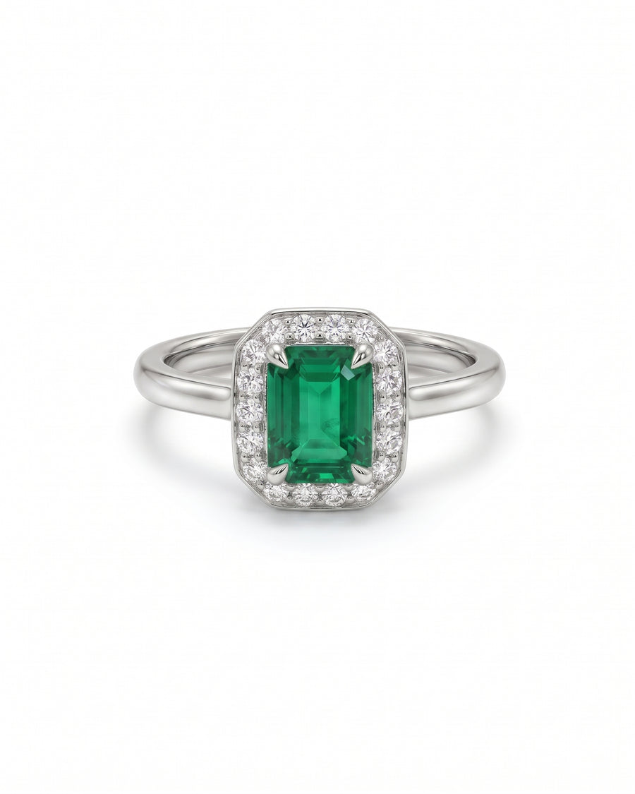 Platinum engagement ring featuring an emerald-cut green gemstone surrounded by a halo of small lab-grown diamonds.