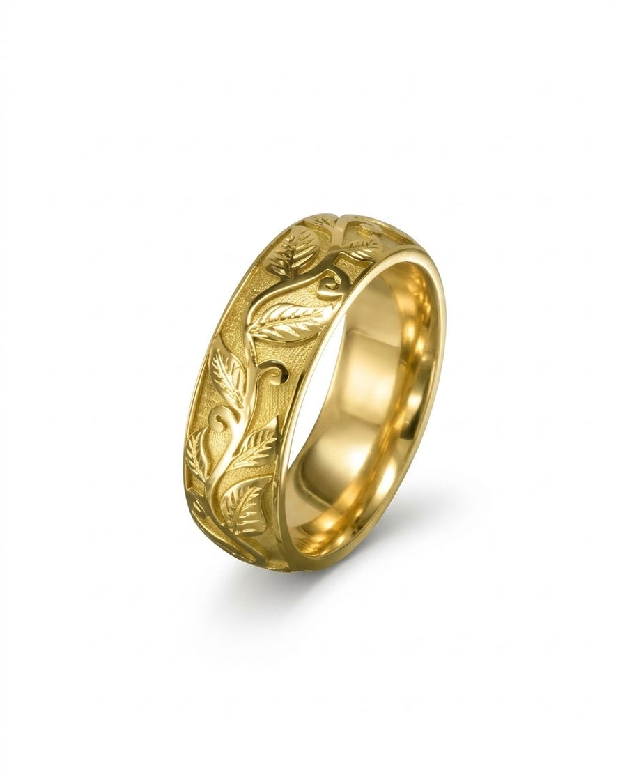 Gold wedding ring with an embossed leaf and vine motif on a textured background.