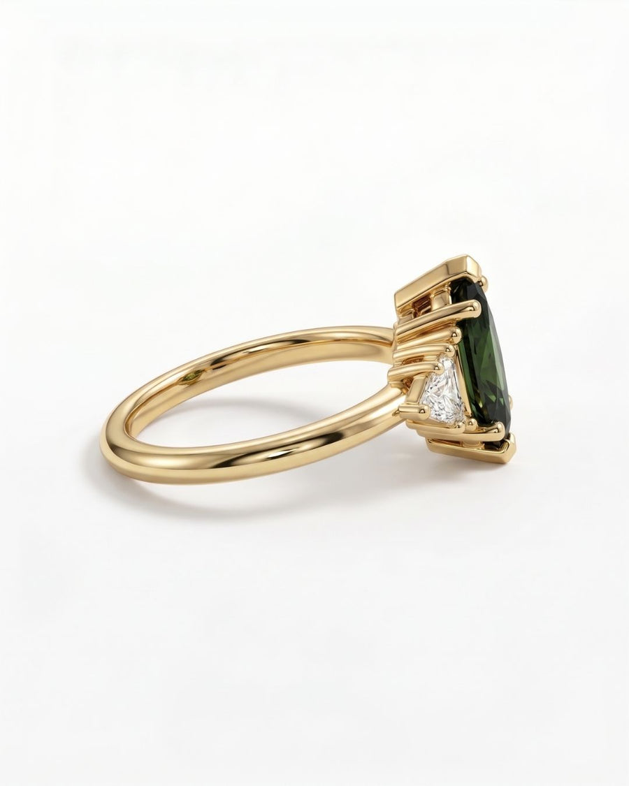 Gold engagement ring featuring a marquise-cut green sapphire with trillion-cut side stones in a claw setting.