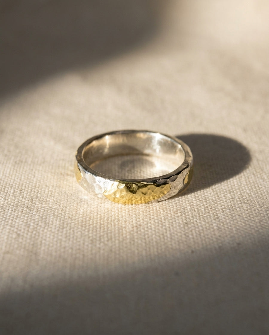 3mm court ring in hammered silver and 9ct yellow gold on a textured fabric background.