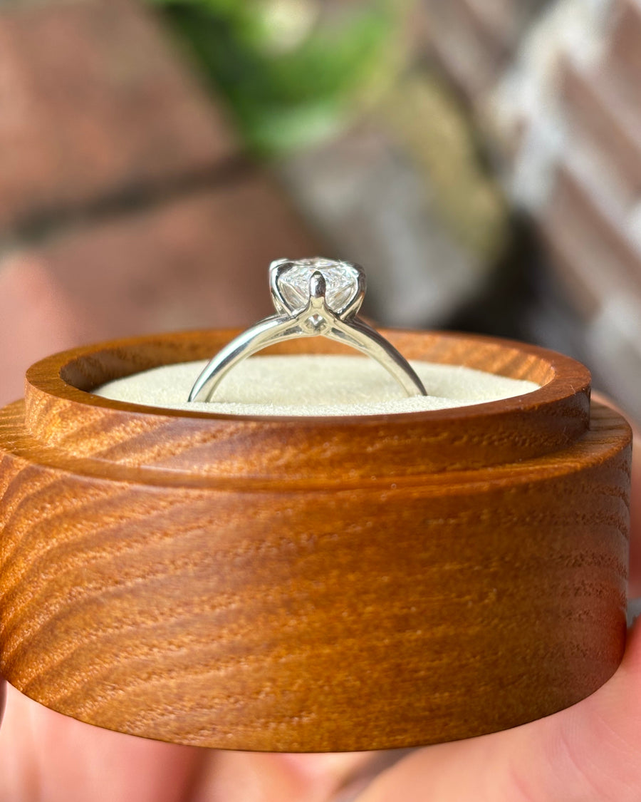 Marquise cut diamond engagement ring in a silver-toned metal setting with tulip-style prongs in a wooden box.