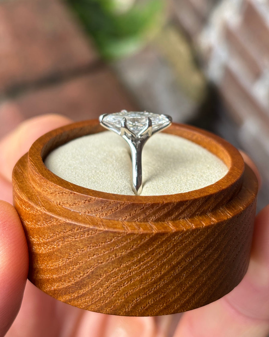 Marquise cut diamond engagement ring with a platinum tulip claw setting in a wooden ring box.