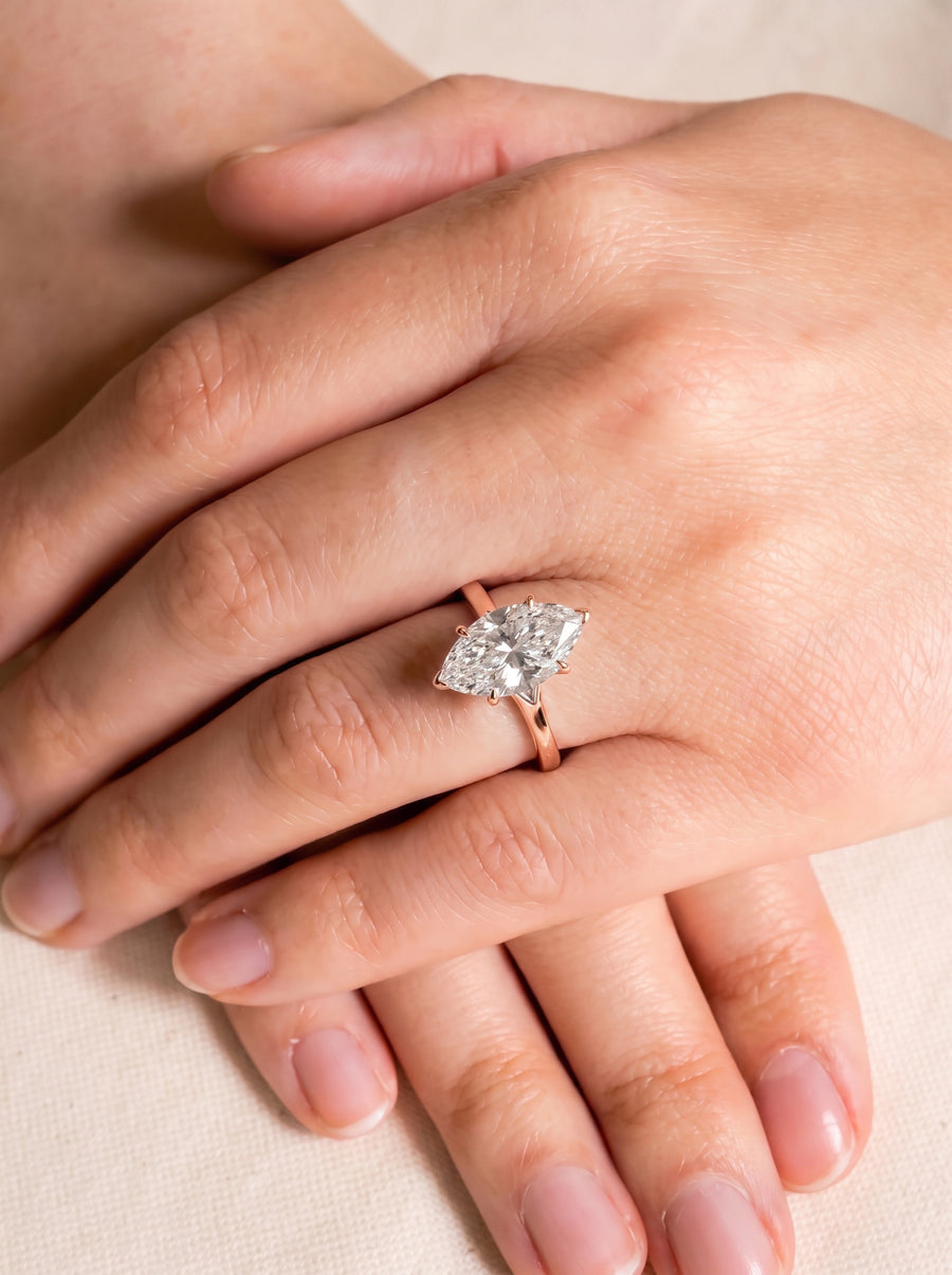 Marquise cut diamond engagement ring set in a rose gold tulip claw setting on a finger.