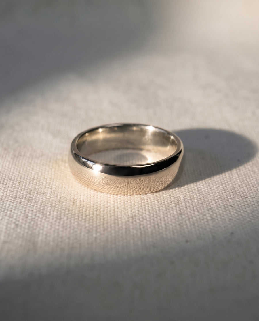 4mm polished 9ct white gold low court wedding ring on a textured fabric surface.