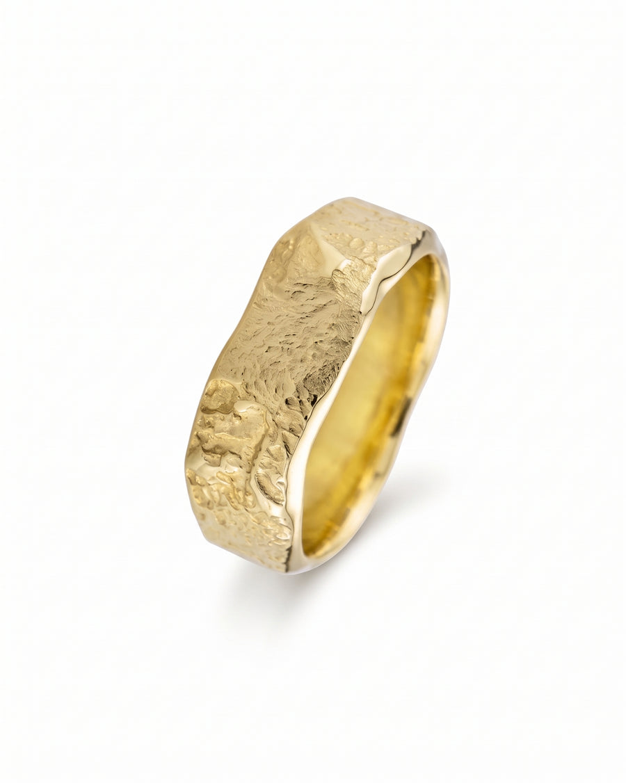 Gold wedding band with a hammered, textured finish and an organic, wavy edge design on a white background.